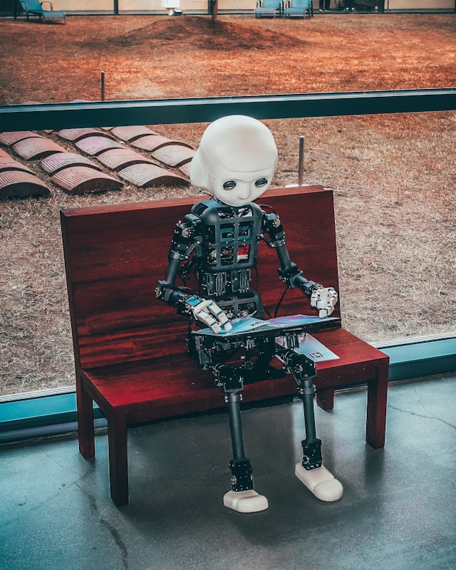 Little robot sitting on a bench reading a magazine